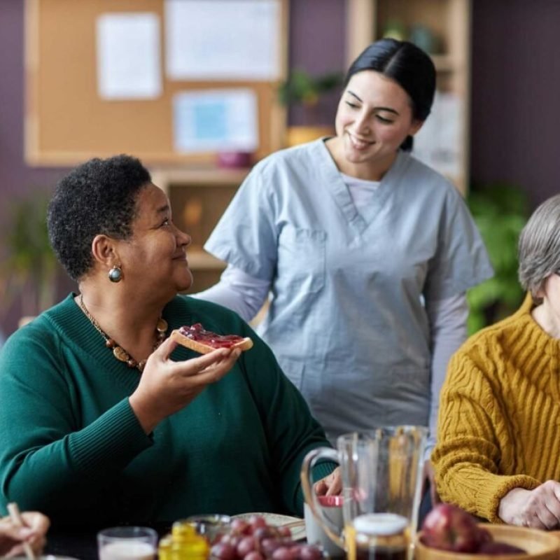 young-nurse-assisting-senior-people-during-breakfa-V26QWH7-1024x683